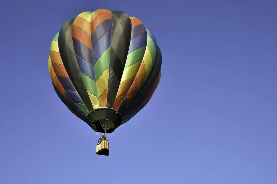 Bunter Heißluftballon steigt in den blauen Himmel auf