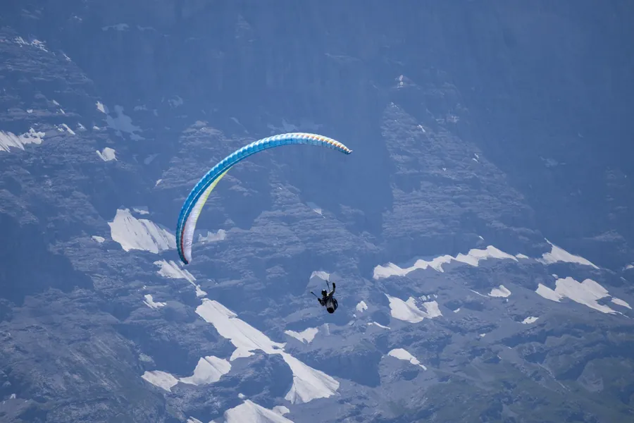 Gleitschirmflieger vor Alpenpanorama im Sinkflug