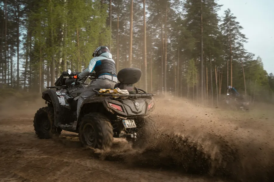 Person fährt mit einem Quad über einen Waldweg
