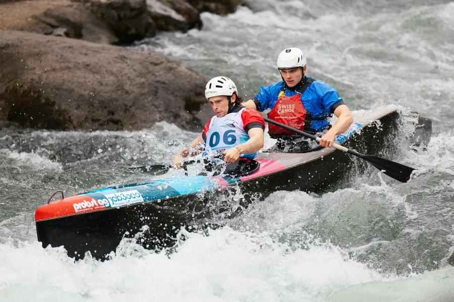 Rafting-Gruppe mit Guide paddelt durch ein Wildwasser in den Schweizer Alpen