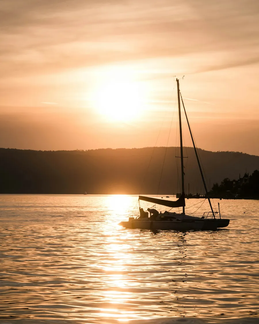 Sonnenuntergang über dem Bodensee mit Boot-Silhouette auf dem Wasser